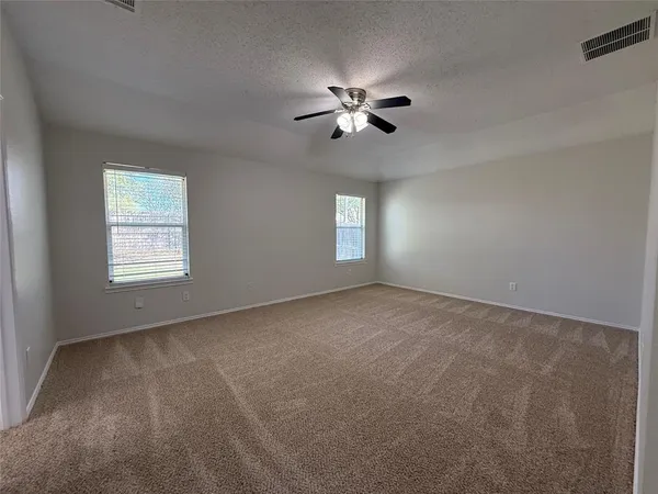 a view of an empty room with a chandelier fan and windows