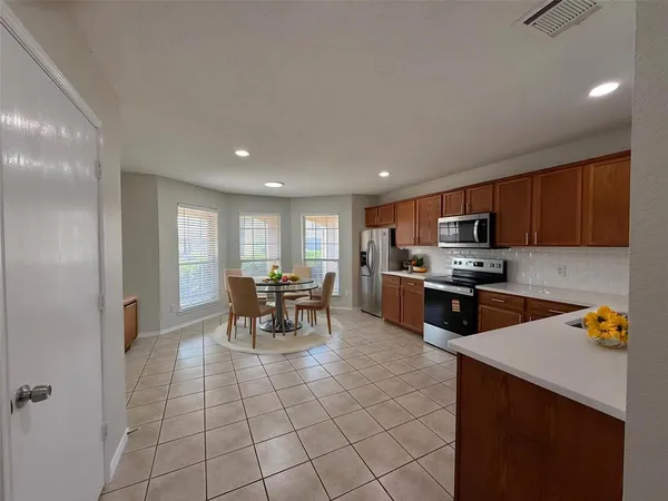 a large kitchen with a stove a sink dishwasher and a refrigerator with wooden floor