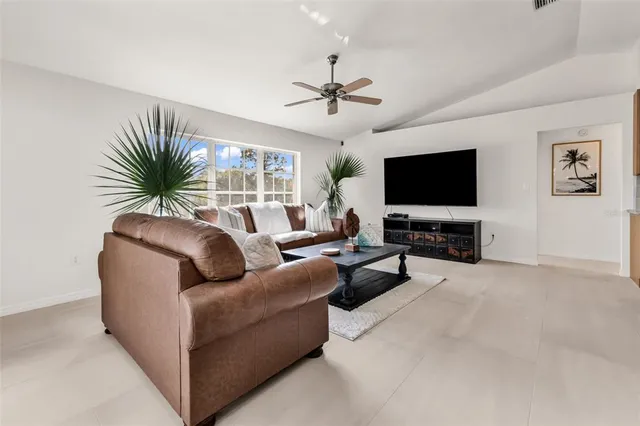 a living room with furniture a flat screen tv and a large window