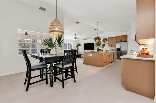 a large kitchen with stainless steel appliances kitchen island a large counter top a stove a chimney a sink and a living room view