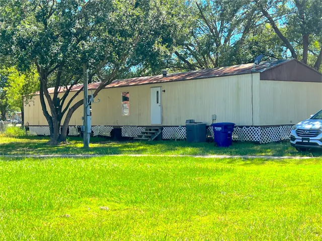 a backyard of a house with wooden fence and large trees