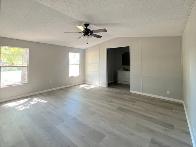 a view of an empty room with window and wooden floor