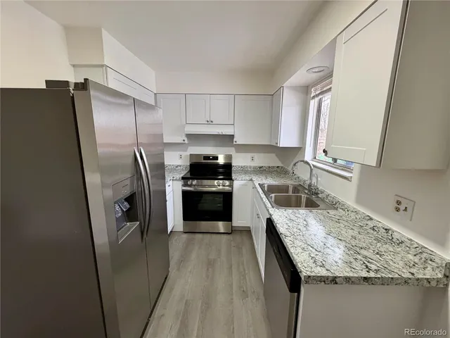 a kitchen with a granite countertop refrigerator a sink a stove a washer dryer and a refrigerator