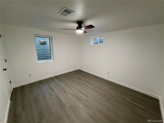 an empty room with wooden floor ceiling fan and window