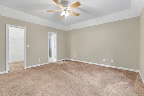 an empty room with a chandelier fan and windows