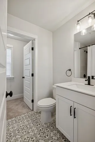 a bathroom with a toilet sink vanity and mirror