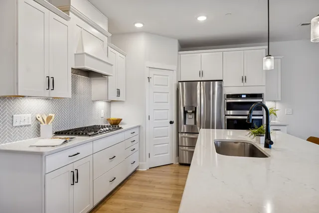 a kitchen with stainless steel appliances kitchen island granite countertop a refrigerator and a sink