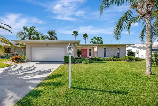 a front view of a house with a yard and potted plants