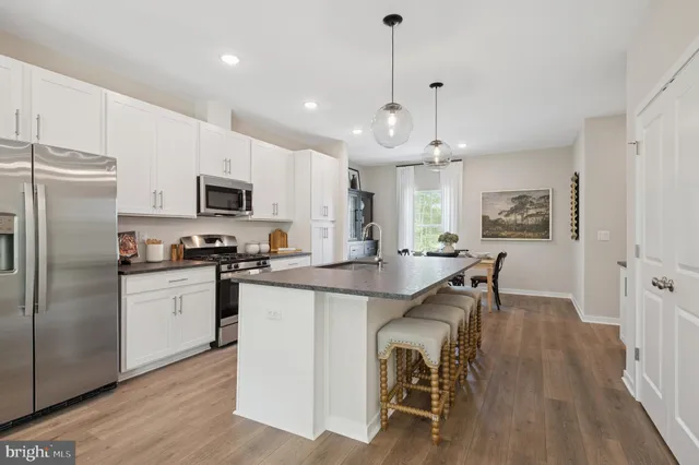 a kitchen with kitchen island a white counter top space stainless steel appliances and cabinets