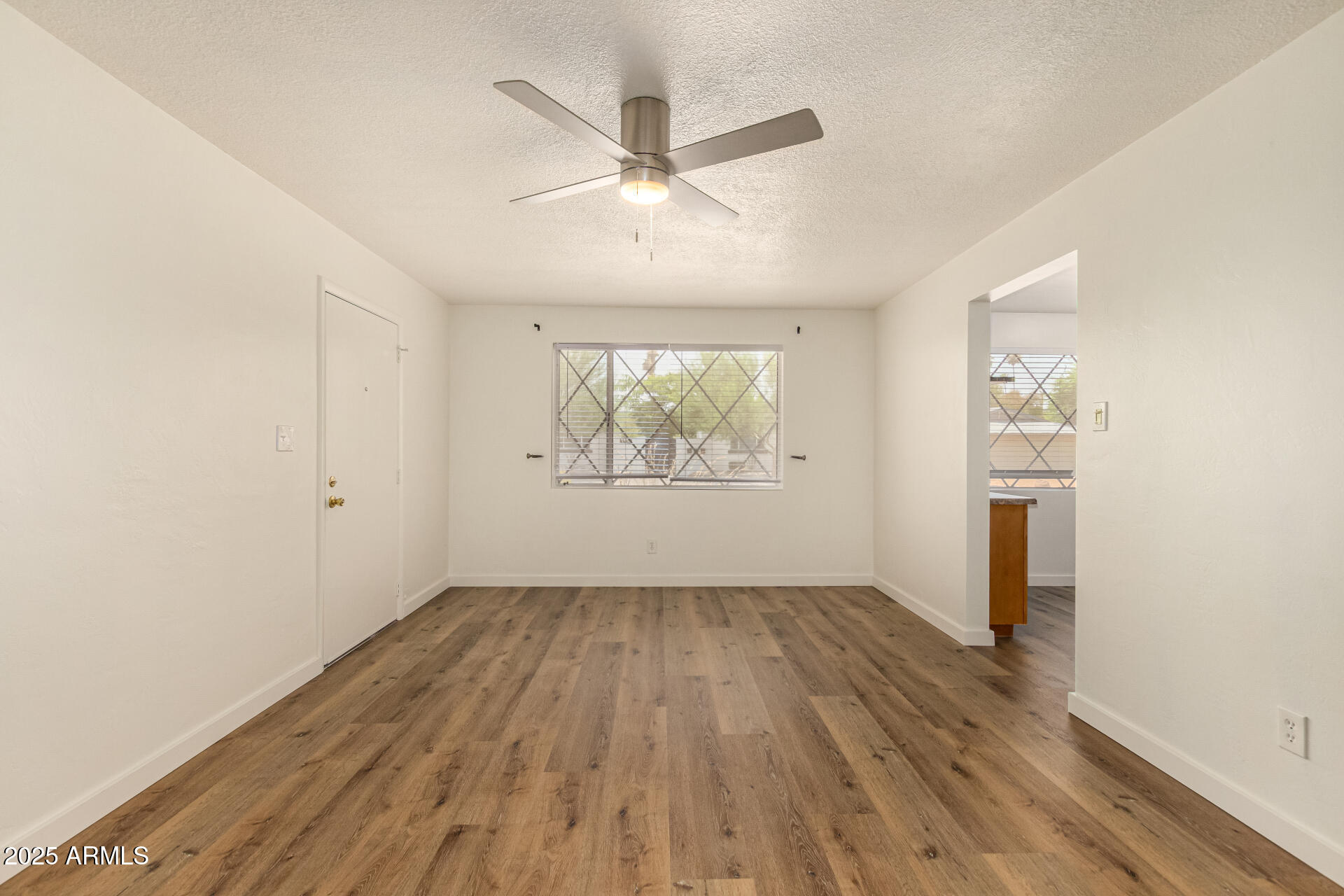 3540 East Montecito Avenue, Unit 1 Phoenix, AZ 85018 - Photo 9 of 26 an empty room with wooden floor a ceiling fan and windows