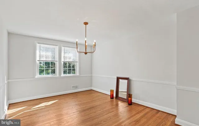 a view of empty room with wooden floor and window