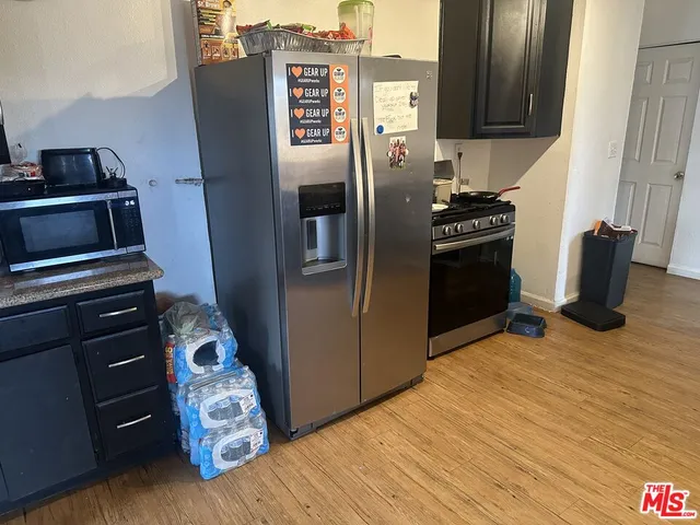 a kitchen with metallic refrigerator and wooden floor