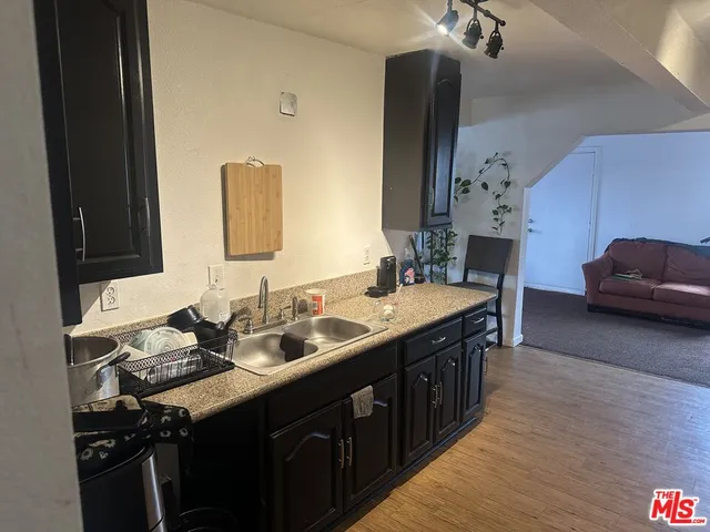 a kitchen with a sink and a stove with wooden floor
