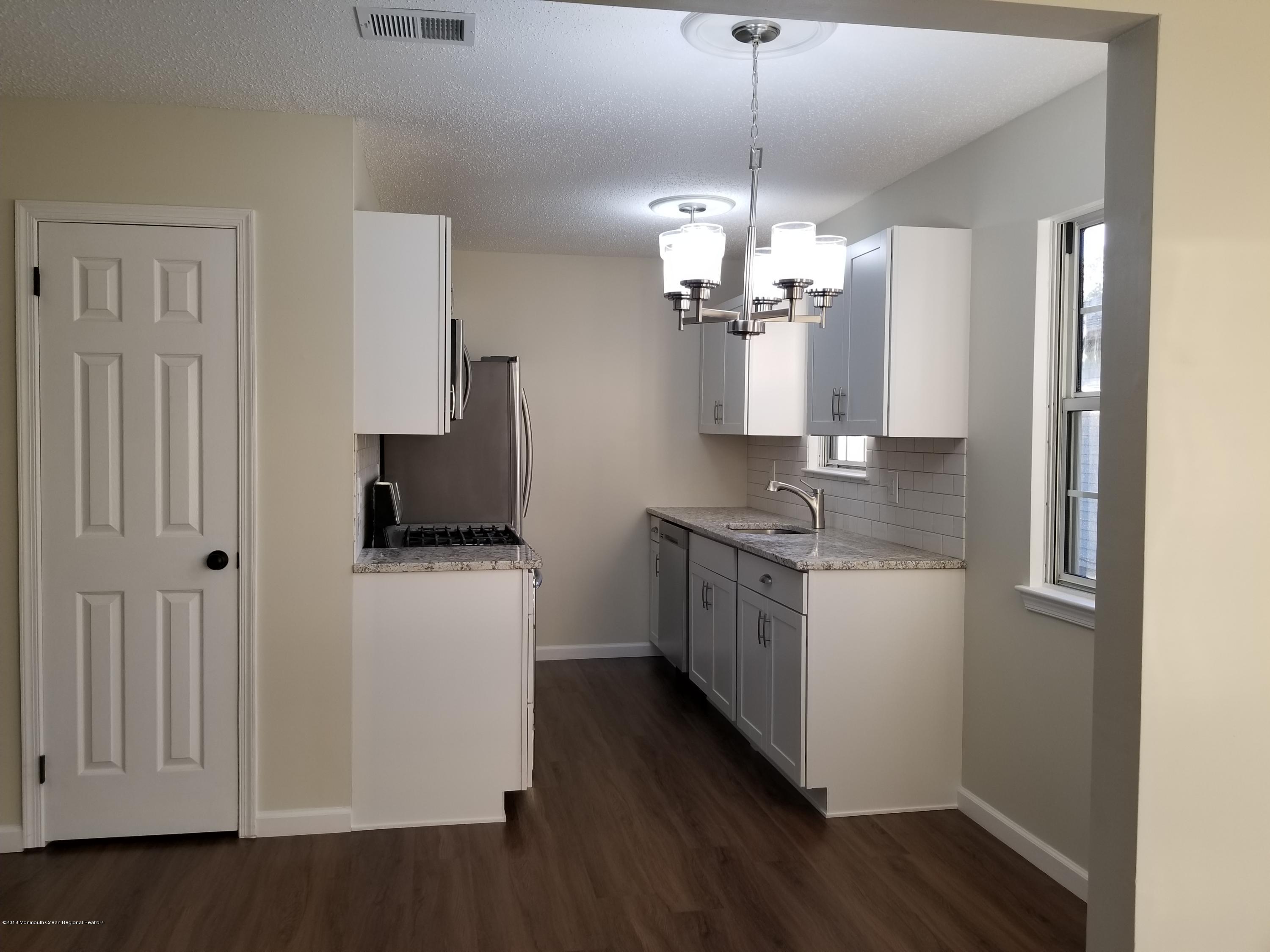 33 Ivy Ridge Close, Unit 1000 Freehold, NJ 07728 - Photo 11 of 31 a kitchen with stainless steel appliances granite countertop a refrigerator a stove a sink dishwasher and a dining table with wooden floor