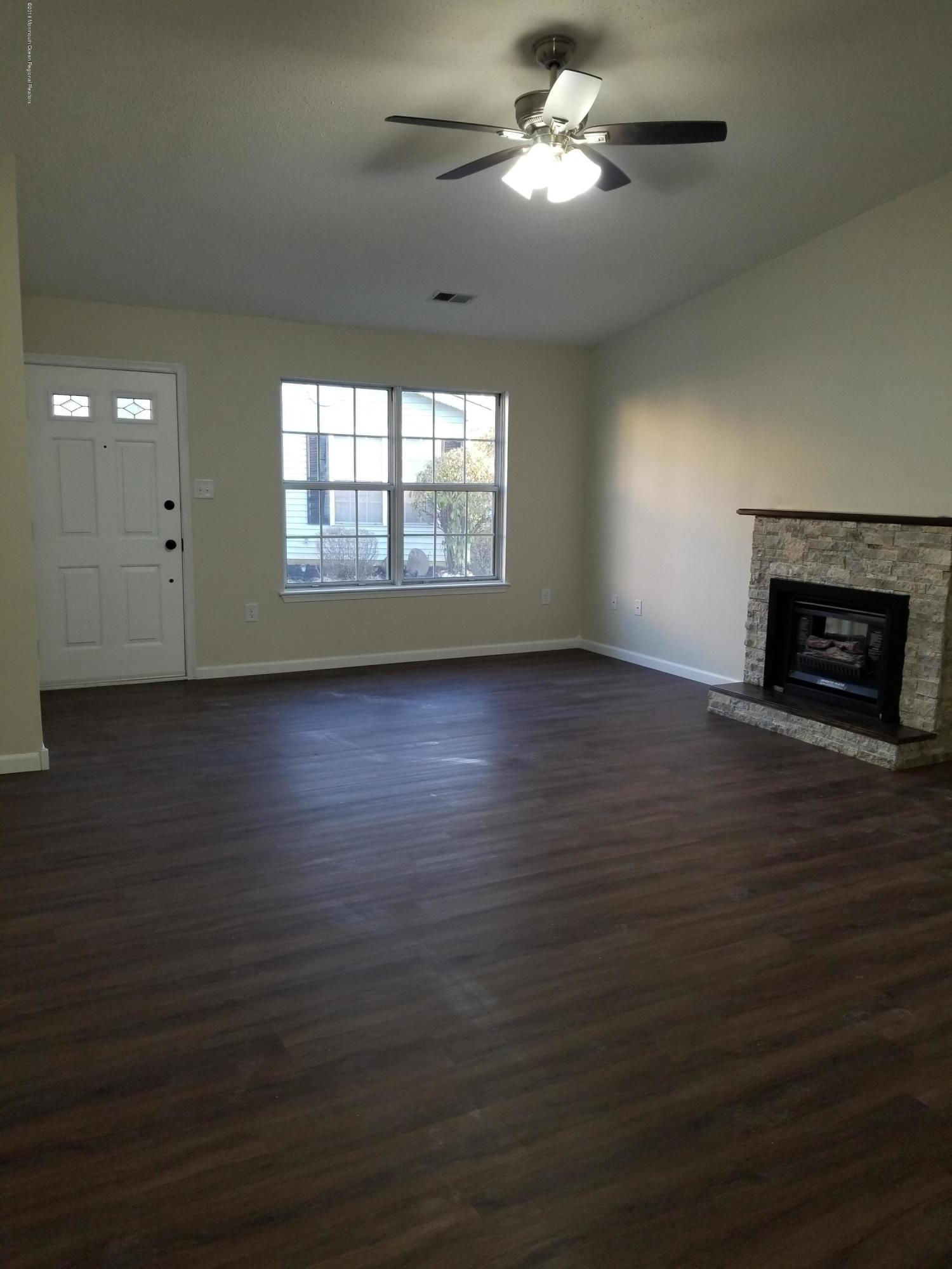 33 Ivy Ridge Close, Unit 1000 Freehold, NJ 07728 - Photo 12 of 31 an empty room with wooden floor chandelier fan and windows