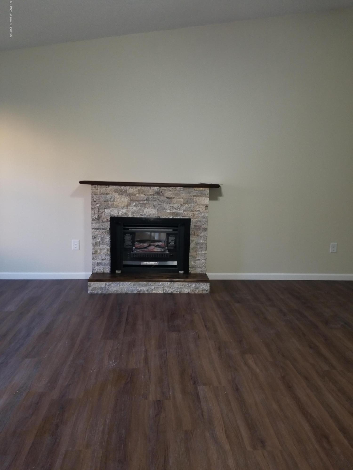 33 Ivy Ridge Close, Unit 1000 Freehold, NJ 07728 - Photo 19 of 31 an empty room with wooden floor and fireplace