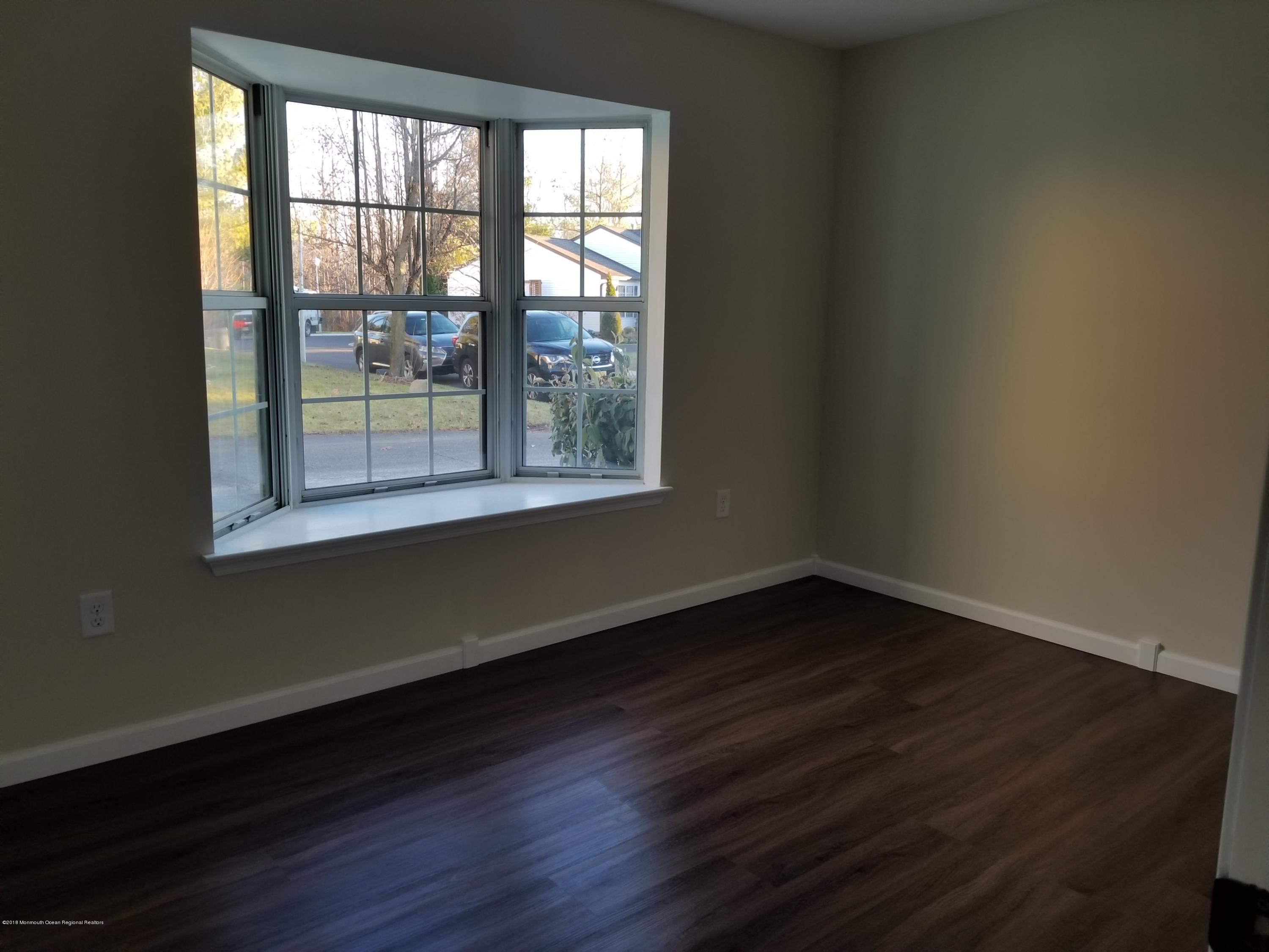 33 Ivy Ridge Close, Unit 1000 Freehold, NJ 07728 - Photo 30 of 31 a view of an empty room with wooden floor and a window