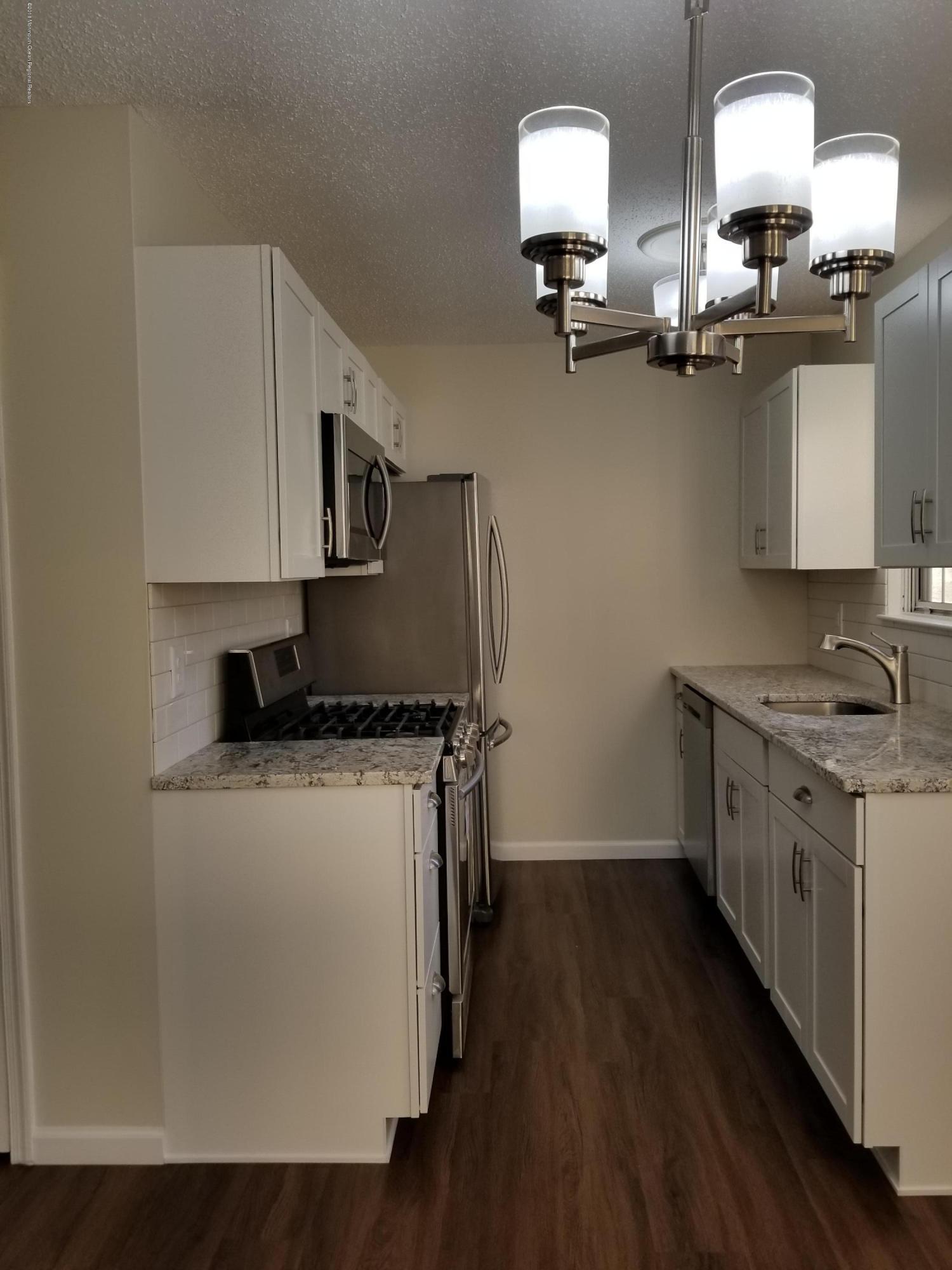 33 Ivy Ridge Close, Unit 1000 Freehold, NJ 07728 - Photo 5 of 31 a kitchen with stainless steel appliances granite countertop a sink stove and microwave