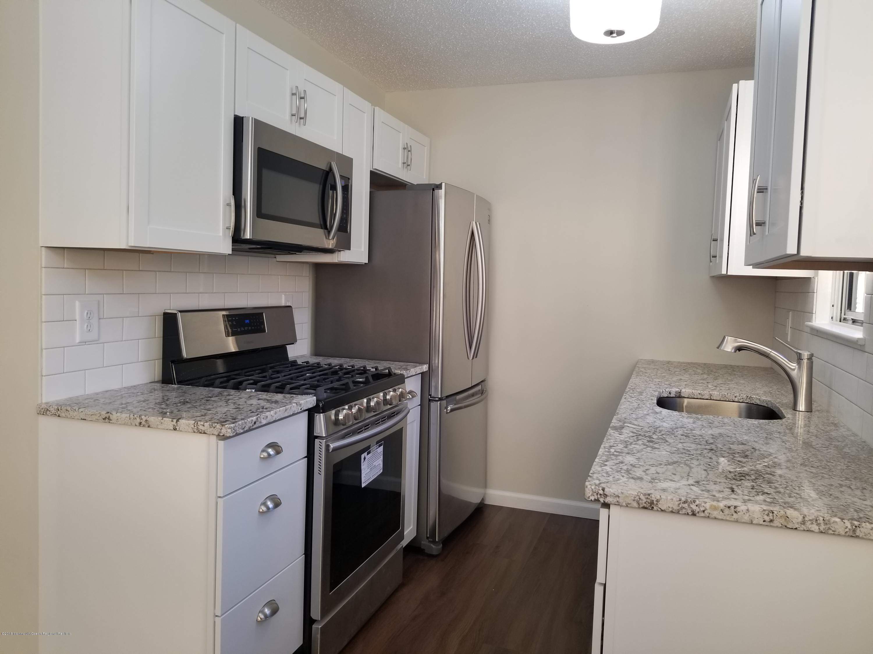 33 Ivy Ridge Close, Unit 1000 Freehold, NJ 07728 - Photo 6 of 31 a kitchen with granite countertop a sink stove and microwave