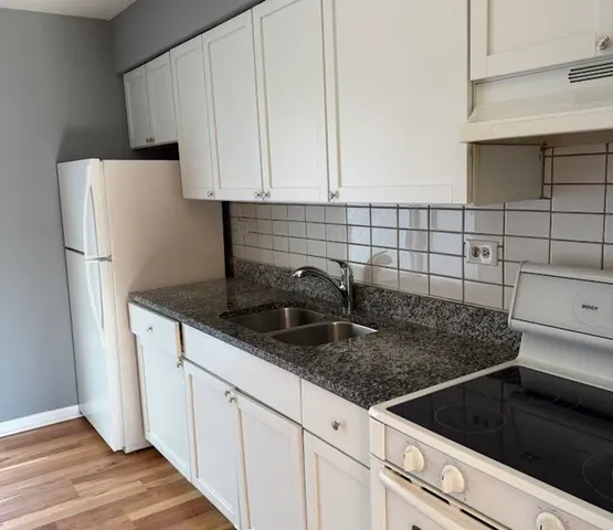 a kitchen with granite countertop white cabinets and white appliances