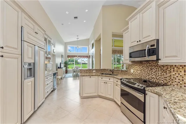 a kitchen with stainless steel appliances granite countertop a stove top oven a sink a refrigerator and a granite counter tops