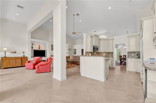 a large white kitchen with lots of white furniture and a chandelier