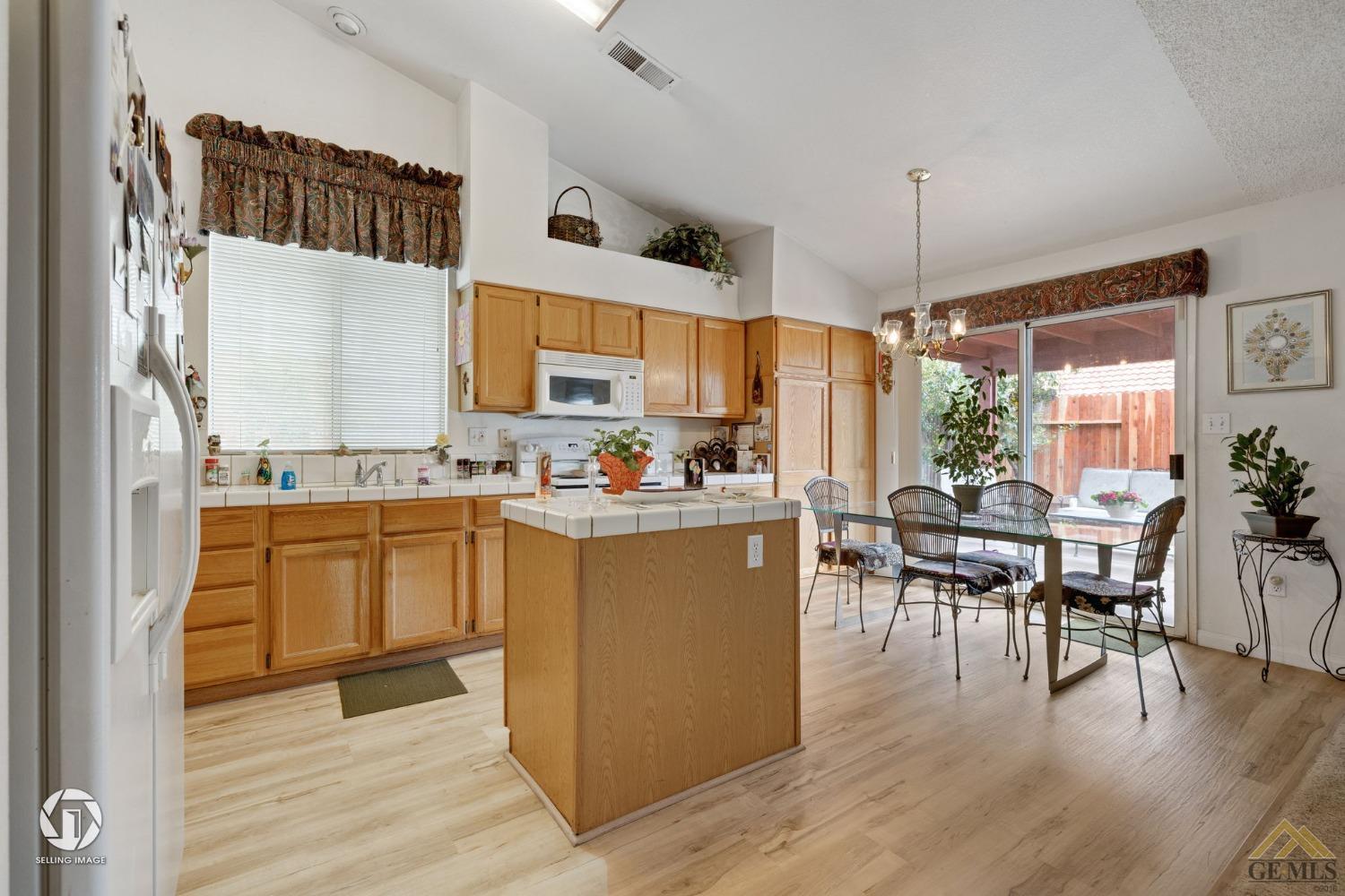 Undisclosed Address Bakersfield, CA 93312 - Photo 33 of 33 a kitchen with stainless steel appliances kitchen island granite countertop a refrigerator a stove a dining table and chairs with wooden floor