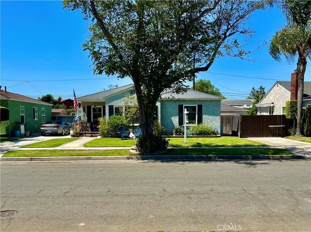 a view of a house with a yard and table and chairs under an umbrella