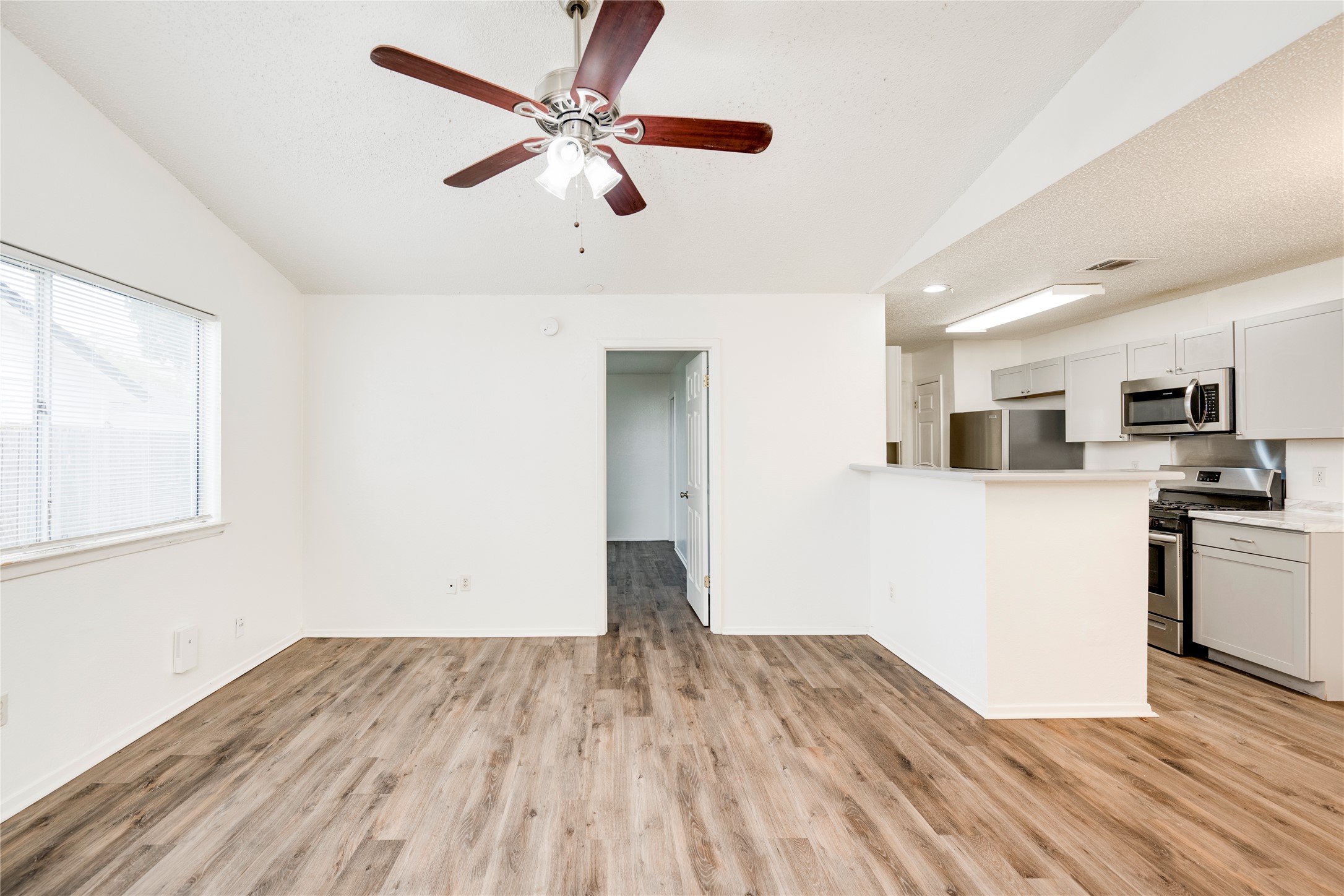 7918 West Gate Boulevard Austin, TX 78745 - Photo 16 of 31 A well-lit living area features wood flooring, a ceiling fan, and seamless access to the kitchen.