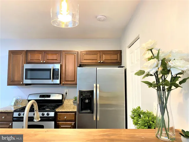 a kitchen with stainless steel appliances granite countertop a refrigerator a stove a microwave cabinets and wooden floor