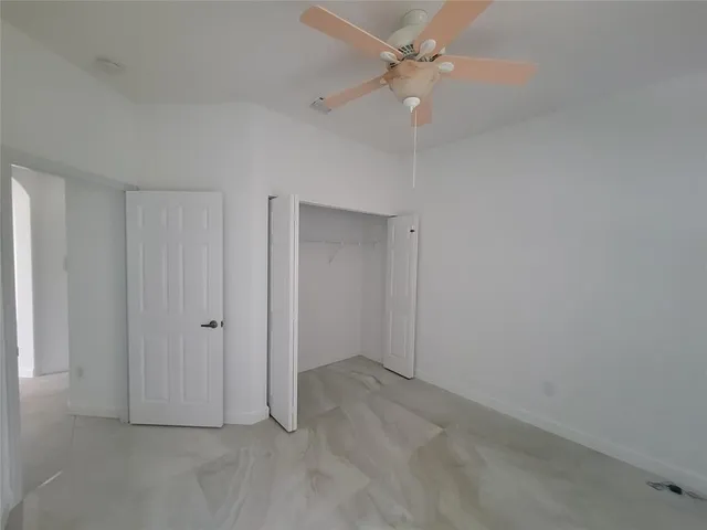 an empty room with a ceiling fan and a window