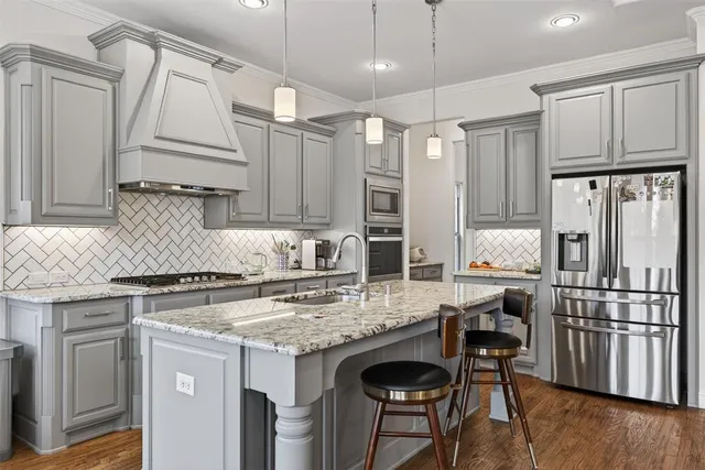 a kitchen with stainless steel appliances granite countertop a stove refrigerator sink and cabinets