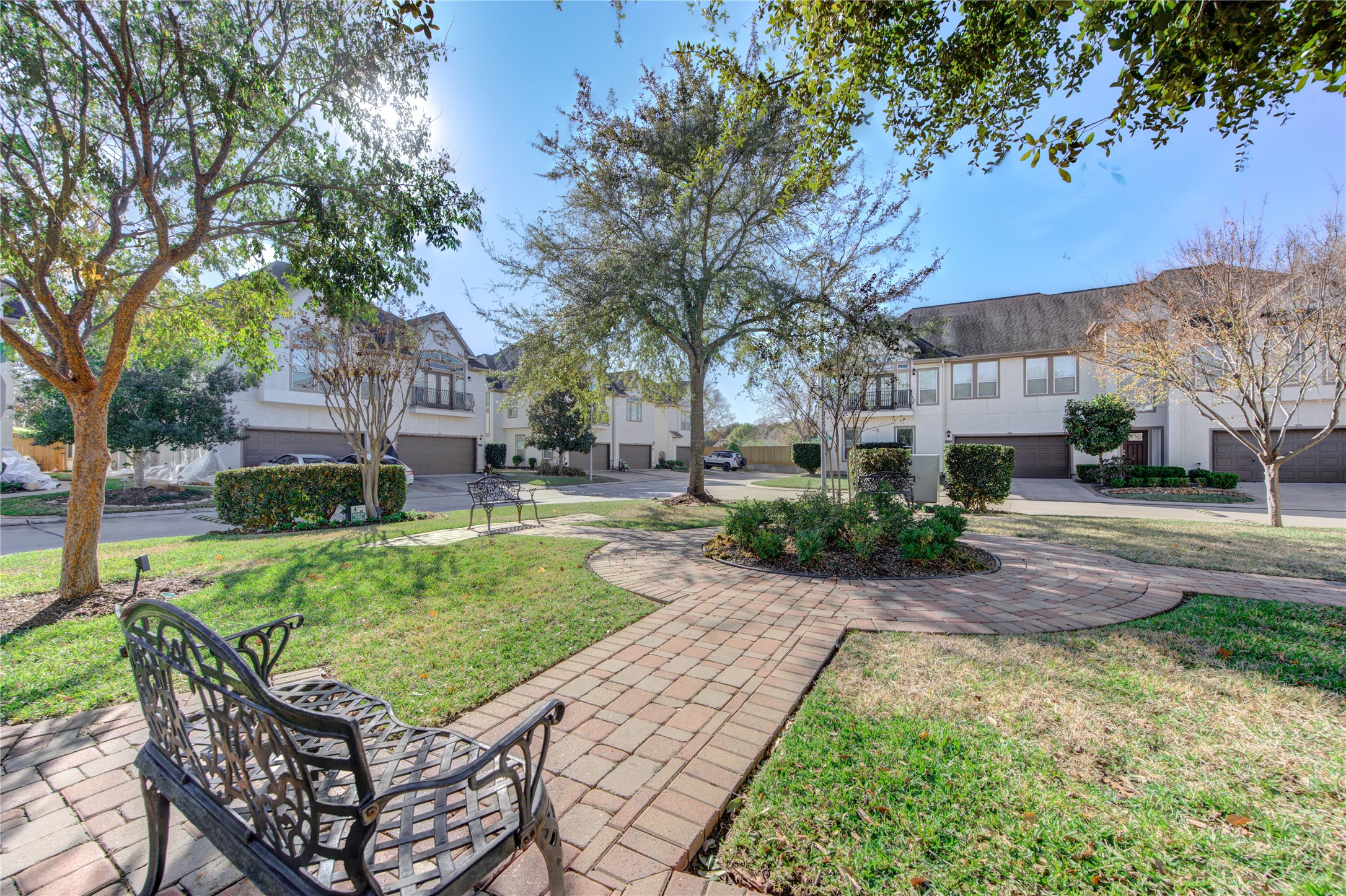 1419 Baldwin Square Lane Houston, TX 77077 - Photo 41 of 45 This serene neighborhood photo showcases a charming, landscaped courtyard with a central tree, surrounded by well-maintained townhouses. The area features a brick pathway and inviting benches, creating a welcoming atmosphere for residents.