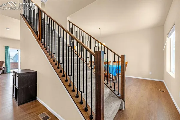a view of staircase with lots of frames on wall and wooden floor