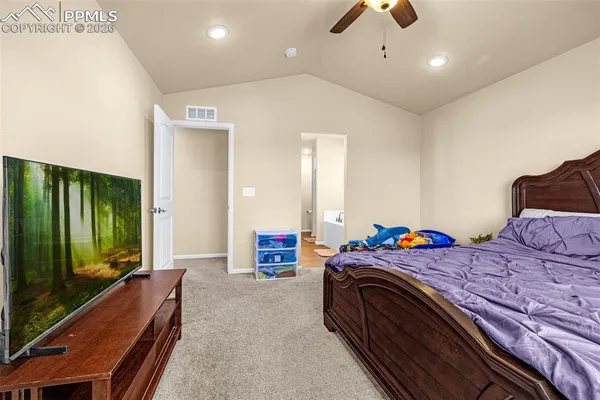 a bedroom with a large bed and a flat tv screen