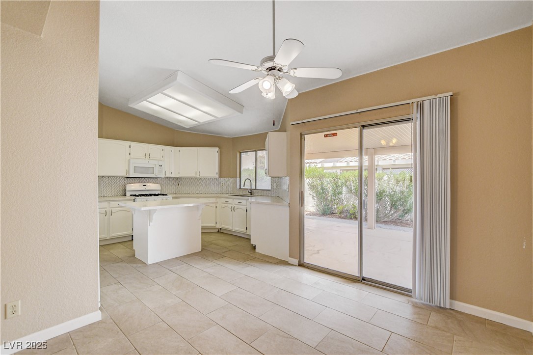 2824 Mayfair Avenue Henderson, NV 89074 - Photo 13 of 46 Kitchen with a island, vaulted ceiling, white cabinets, and tasteful backsplash