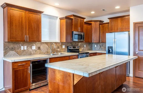 a kitchen with stainless steel appliances a stove a sink a refrigerator a center island and a cabinets