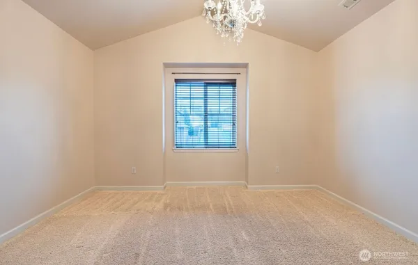 an empty room with a chandelier fan and windows