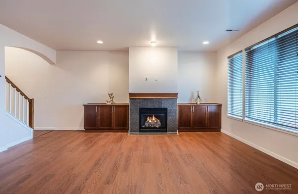 a view of an empty room with wooden floor fireplace and a window