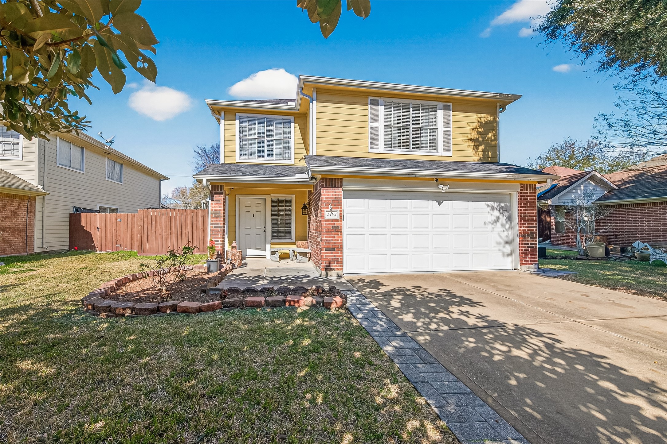 2202 Falling Oaks Road Houston, TX 77038 - Photo 2 of 47 brick accents, a welcoming front porch, and a two-car garage. The driveway leads to a neatly landscaped front yard, offering a spacious and inviting entryway.