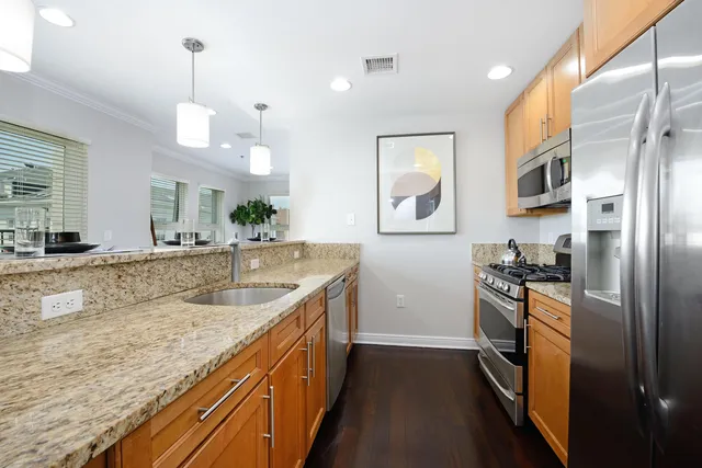 a kitchen with stainless steel appliances granite countertop a sink and a refrigerator