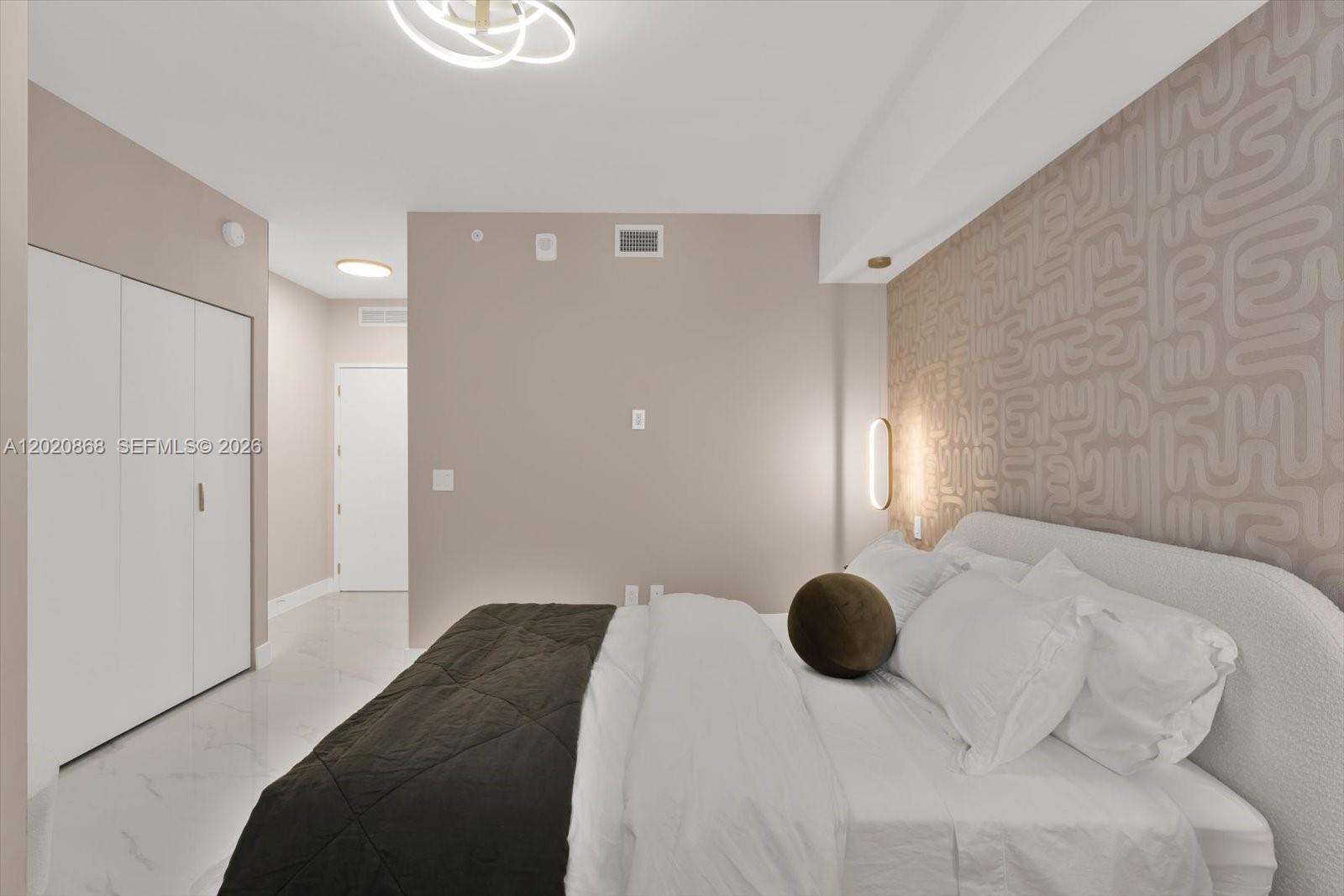 700 Northeast 24th Street, Unit 1602 Miami, FL 33137 - Photo 19 of 30 a bedroom with a bed and a chandelier