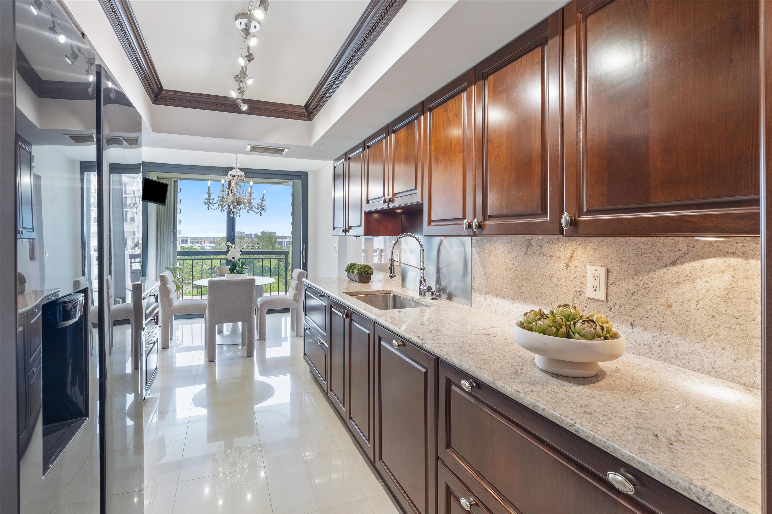 2003 North Ocean Boulevard, Unit 902 Boca Raton, FL 33431 - Photo 11 of 45 a kitchen with stainless steel appliances kitchen island granite countertop a refrigerator a sink dishwasher a dining table and chairs with wooden floor
