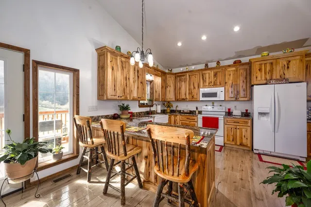 a kitchen with stainless steel appliances kitchen island granite countertop a refrigerator a stove a sink dishwasher and white cabinets with wooden floor