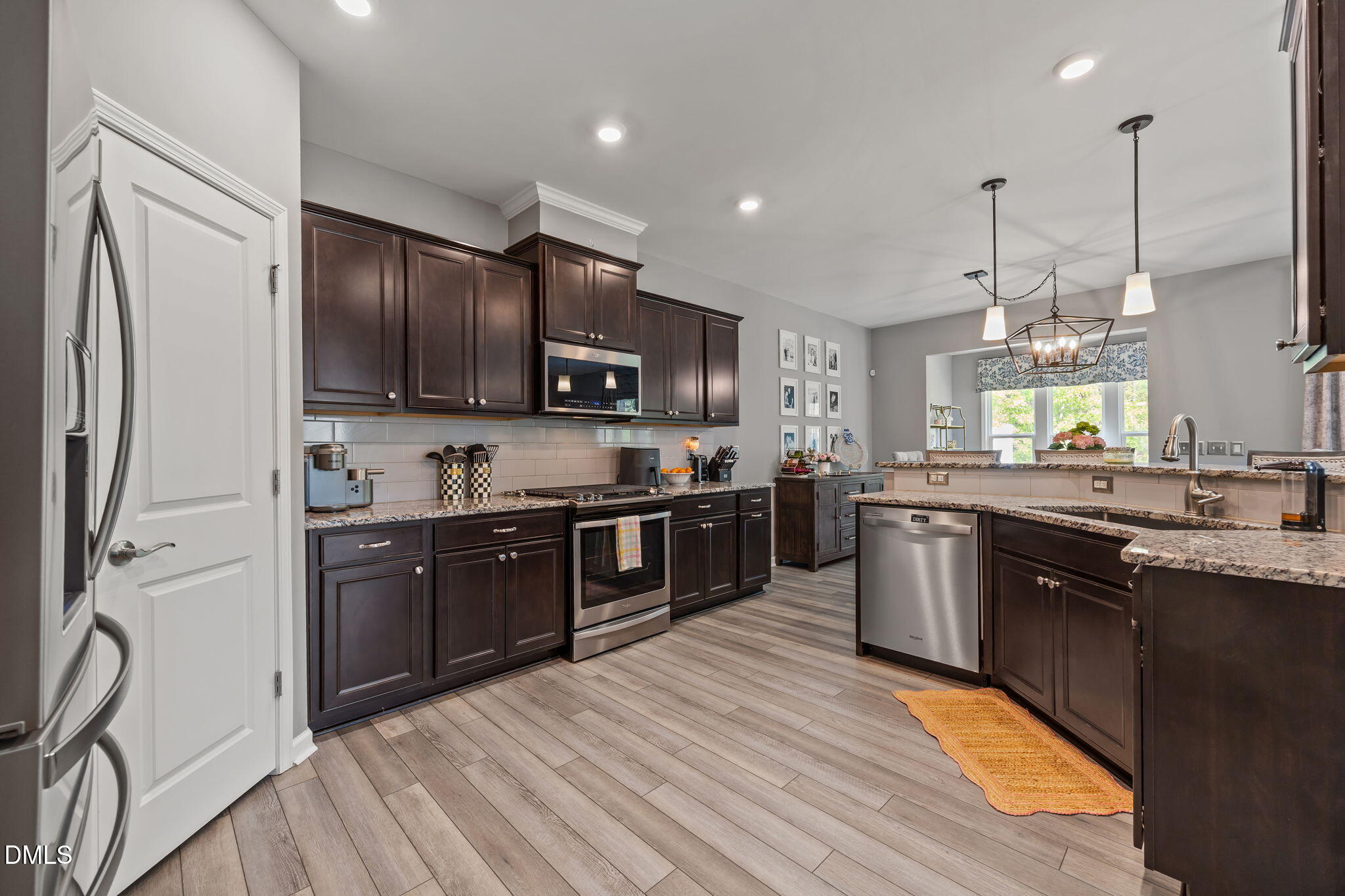 1108 Felman Road Durham, NC 27703 - Photo 7 of 28 a large kitchen with stainless steel appliances granite countertop a stove a sink dishwasher a refrigerator and a dining table with wooden floor