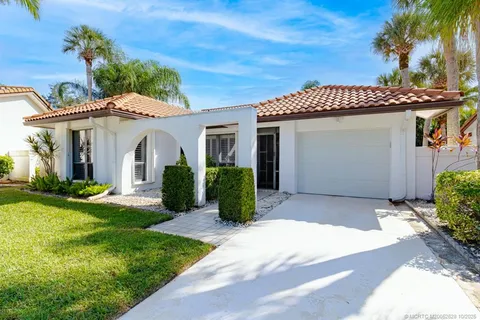 a view of a white house with a small yard and potted plants