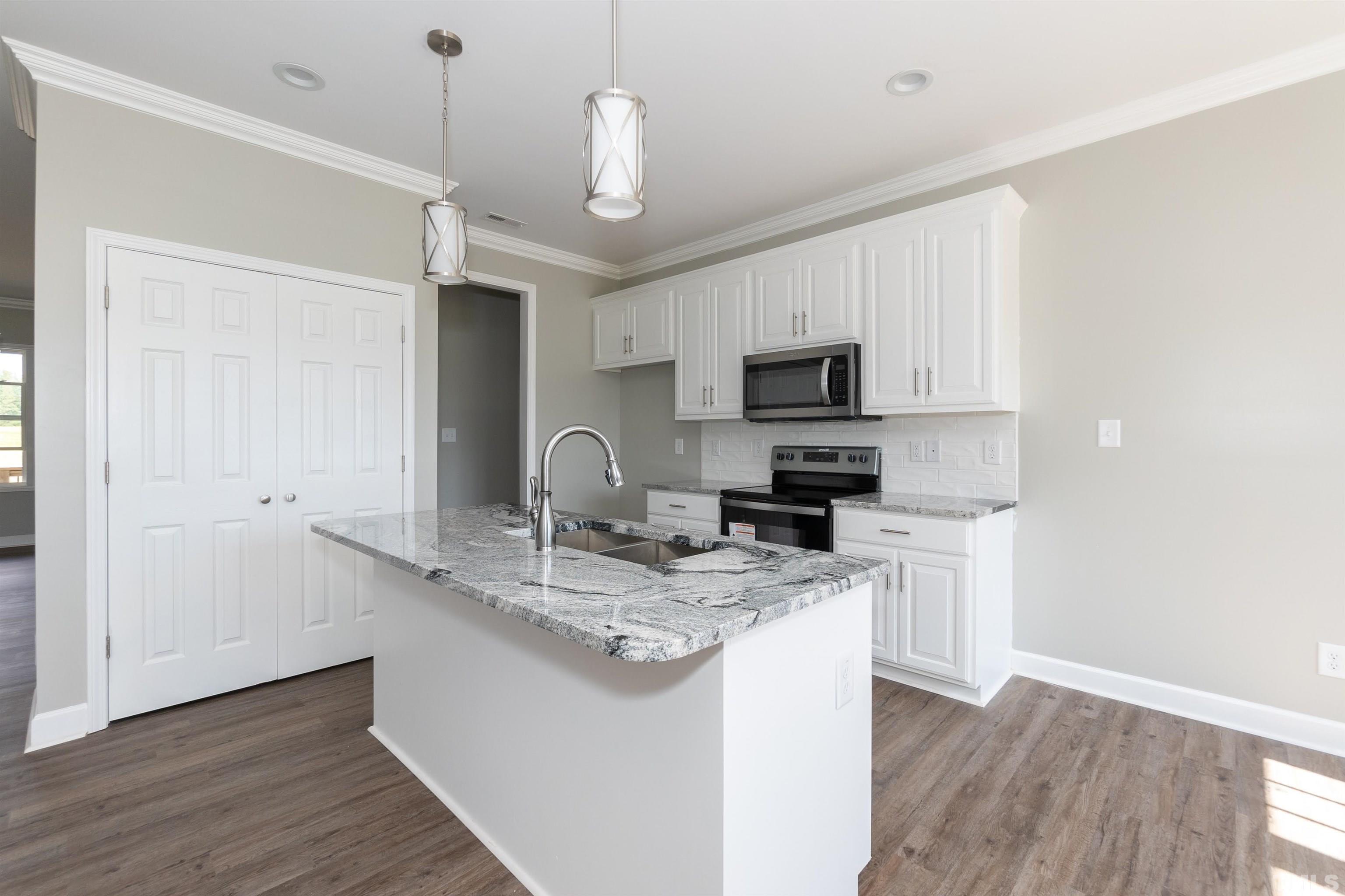7149 Hill Road Spring Hope, NC 27882 - Photo 16 of 21 a kitchen with kitchen island granite countertop stainless steel appliances a sink cabinets and wooden floor