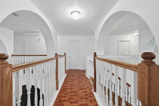a view of a hallway with wooden floor and stairs