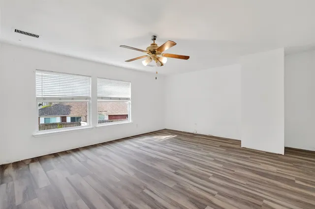 an empty room with wooden floor and windows
