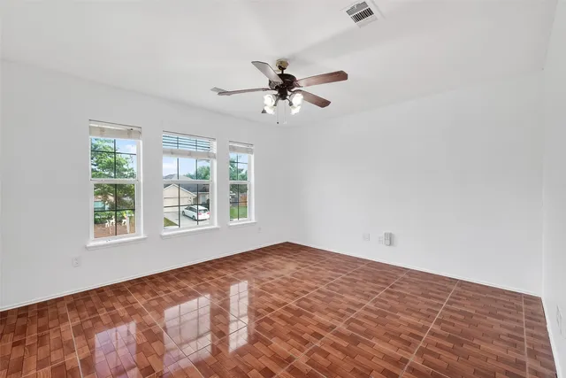 an empty room with windows and fan